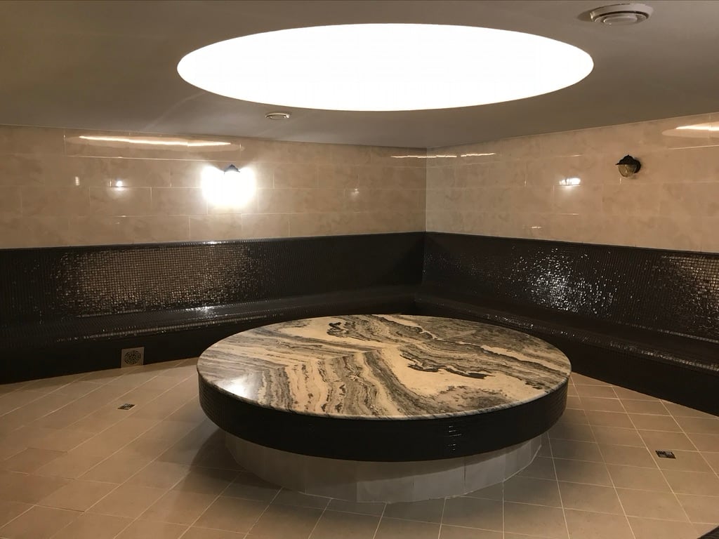Круглый каменный стол и мозаичная скамья в хаммаме